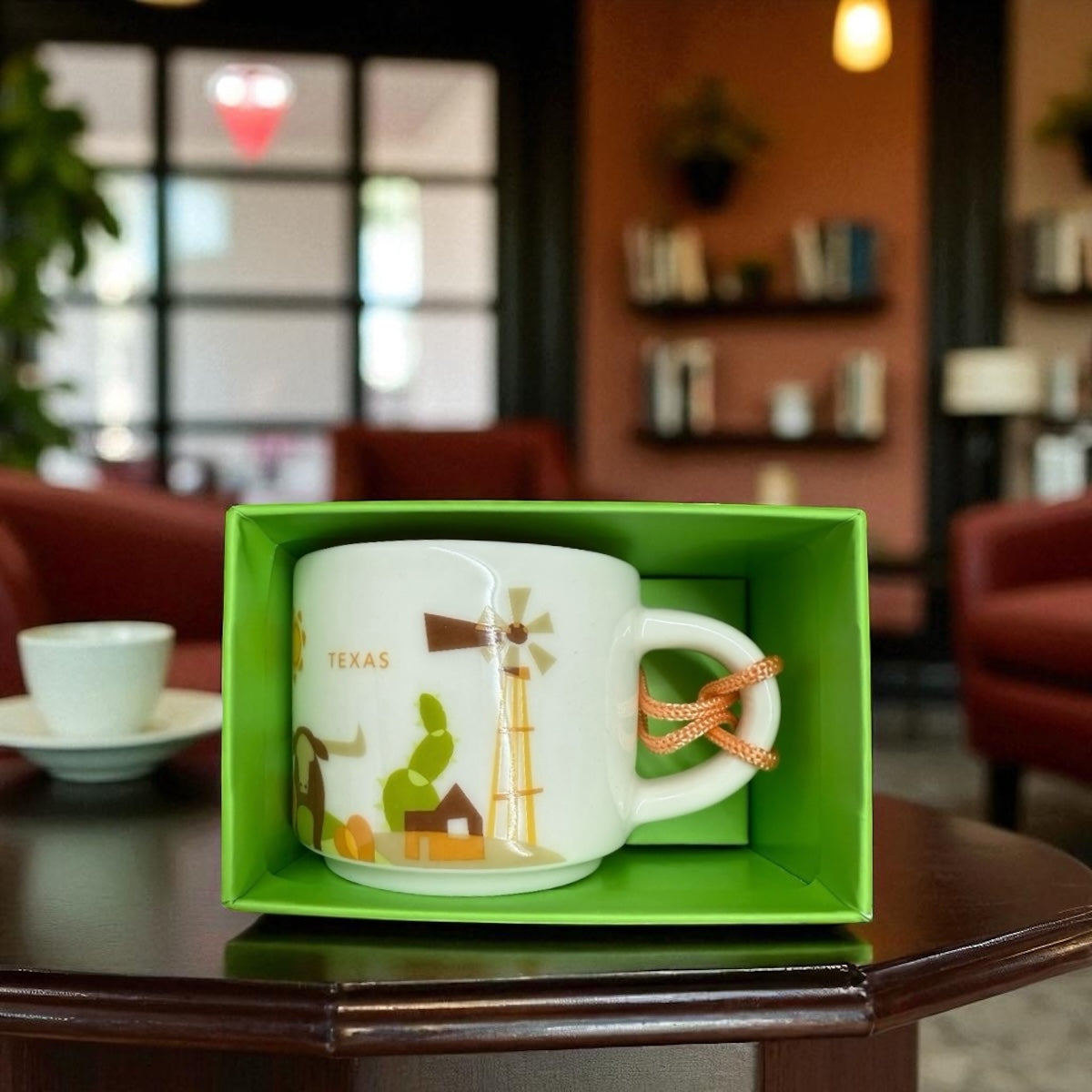 White mug with Texas design in a green box on a table in a blurred cafe setting